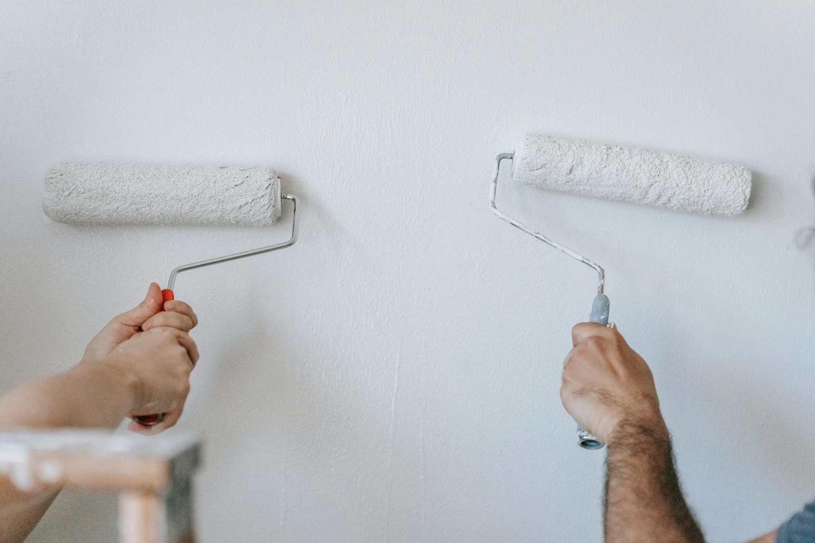Hands rolling fresh paint onto an interior wall