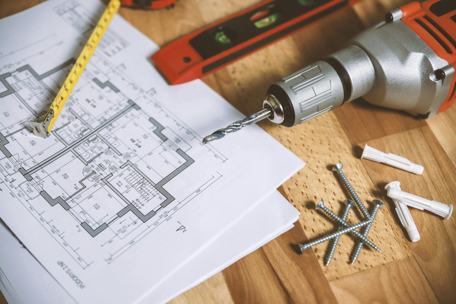Drill, plans and measuring tools laid out on a workbench