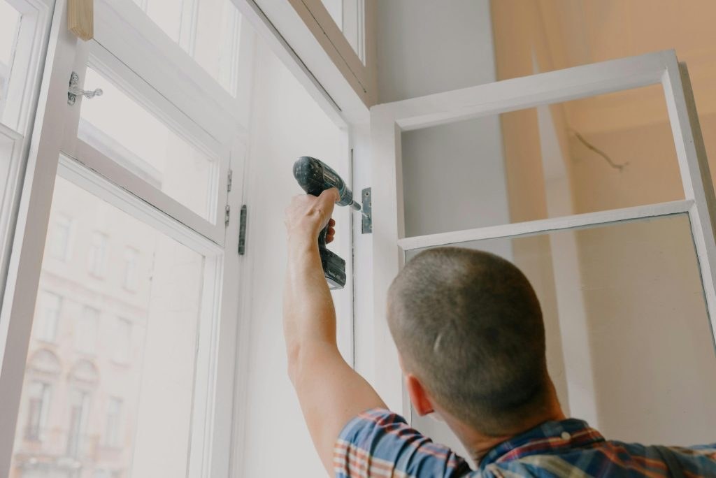 Worker installing a fitting with a power drill