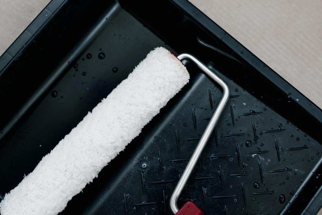A paint roller resting in its tray