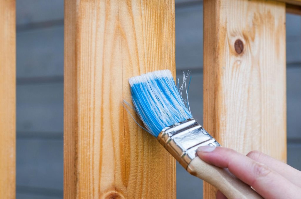 A hand painting wooden boards with a brush